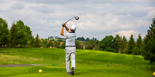 Man driving a golf ball on a course